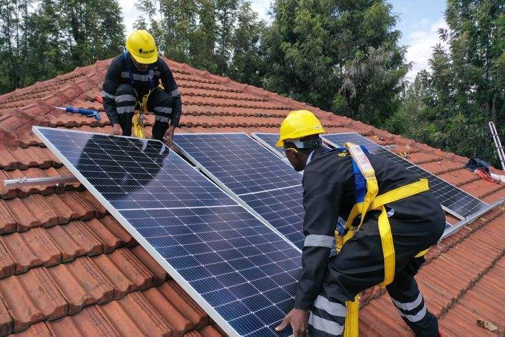 Installers fitting solar panels onto a tiled residential roof