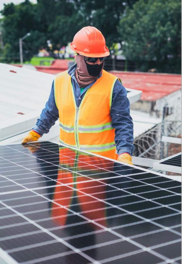 Technician installing a solar panel on a rooftop